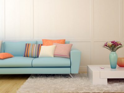 Bright composition of a light blue sofa with cushions  and a white table on the white carpet